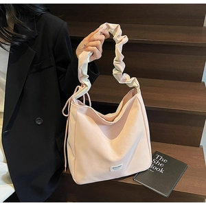 Pink dopamine tote bag with unique ruched handles and branded label on dark stairs