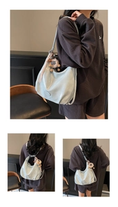 Détail du sac cabas en cuir souple bleu clair avec pompon décoratif et logo embossé