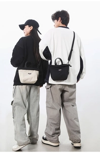 Detail view of canvas crossbody bags in black and beige with adjustable straps on models