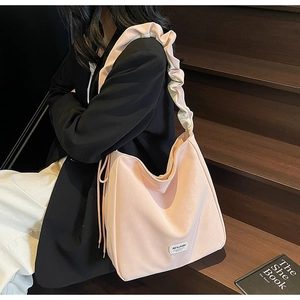 Detail of light pink tote bag featuring unique ruffled shoulder strap and side drawstrings