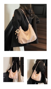 Détail du sac hobo en cuir verni rose clair avec pendentif lion en peluche et texture souple