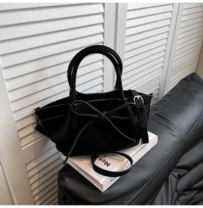 Détail du sac à main en cuir grainé noir avec nœud élégant et finitions métalliques argentées