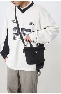 Detail of black nylon drawstring crossbody bag with logo patch and adjustable strap