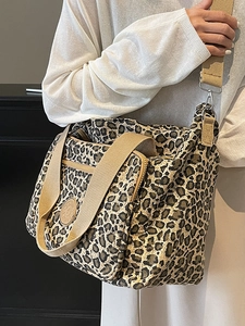 Stylish leopard print canvas tote bag with wide shoulder strap worn by a model