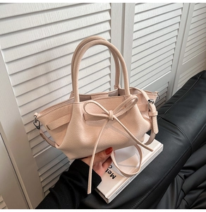 Détail d'un sac à main rose avec un nœud élégant et une finition en cuir texturé