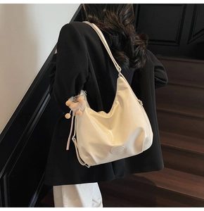 Grand sac hobo crème brillant porté par un mannequin, style urbain chic et minimaliste