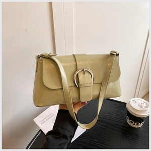 Detail of light green oil wax leather underarm bag with silver round buckle in a cafe setting