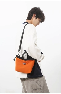 Detail of a minimalist orange and black crossbody bag with adjustable nylon straps