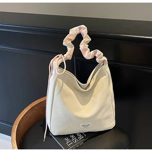 Detail of cream white tote bag with pink ruffled handle and drawstring accents