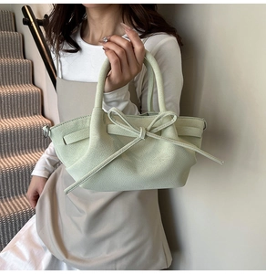 Détail d'un sac à main en cuir vert clair avec texture litchi et un nœud élégant