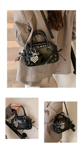 Details der schwarzen Lackleder-Boston-Bag mit seitlichen Schleifen und silbernem Herzanhänger