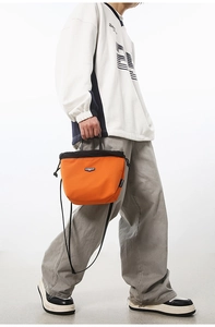 Close-up of bright orange drawstring bucket bag in durable nylon with brand logo detail