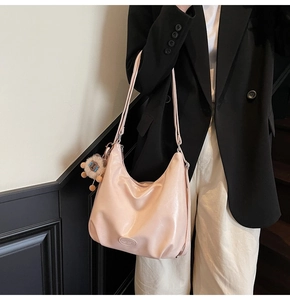 Détail du sac croissant rose clair en cuir souple avec un charmant pendentif en peluche