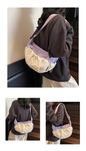 Detail of a color-block dumpling bag featuring purple and beige contrast with side labels
