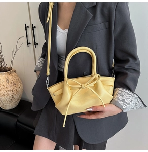 Sac à main jaune tendance avec nœud papillon porté par un mannequin en blazer gris