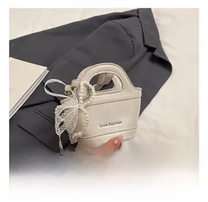 Close-up of white mini handbag with pearl chain, lace bow and glossy leather texture