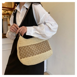 Detail view of the hollow woven mesh texture on the cream summer straw shoulder bag