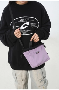 Detail of purple nylon drawstring crossbody bag featuring brand logo and shoulder strap
