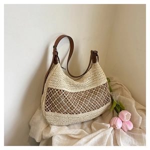 Close-up of hollow woven straw beach bag featuring brown leather shoulder strap and tulips