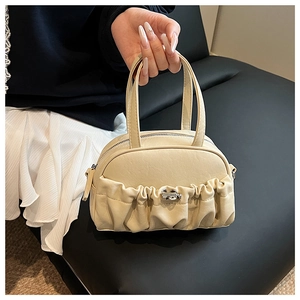 Détail du sac à main plissé crème montrant la texture en similicuir et le fermoir argent