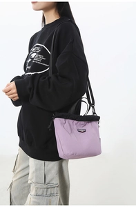 Detailed shot of purple nylon drawstring crossbody bag with logo on a male model