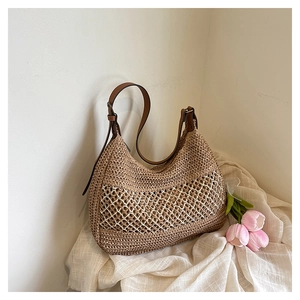 Close-up of retro hollow woven straw hobo bag with brown adjustable leather strap