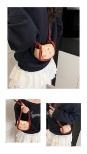 Détail du mini sac selle crème avec motif ours et bordures contrastées de couleur rouge