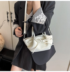 Détail d'un sac à main en cuir blanc cassé avec un nœud élégant et une bandoulière