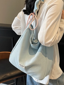 Chic light blue tote bag with pink drawstring and white label worn by a female model