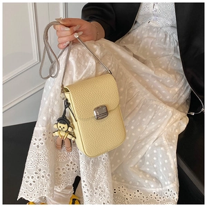 Detail view of yellow lychee leather phone bag with silver chain and cartoon charm