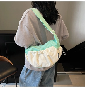 Detail view of contrast color crossbody bag with mint green folds and adjustable strap