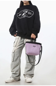 Lifestyle shot of a purple nylon tote bag with black handles and adjustable crossbody strap