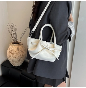 Détail d'un sac seau blanc crème avec un nœud élégant et une texture en similicuir