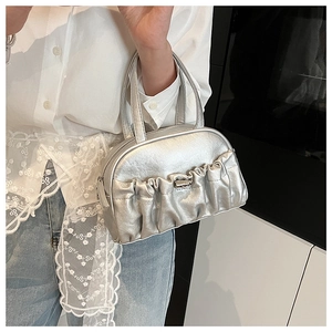 Sac à main argenté plissé à effet métallique porté par un mannequin en tenue décontractée