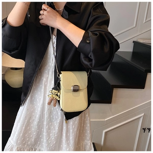 Litchi pattern crossbody bag in cream yellow with metal buckle and cartoon charm detail