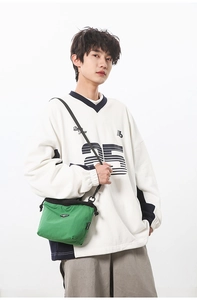Detail of casual color-block messenger bag and oversized sweatshirt on model