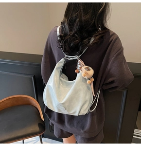 Détail du sac hobo bleu clair brillant avec fines bretelles et pendentif en peluche