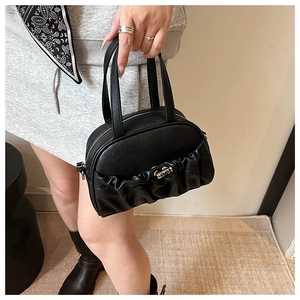 Détail d'un sac oreiller plissé noir avec boucle argentée tenu par un mannequin