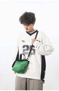 Close-up of green casual crossbody bag featuring black drawstring and shoulder strap