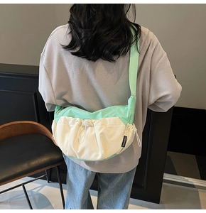 Detail of mint green and cream canvas crossbody bag with drawstring and brand label