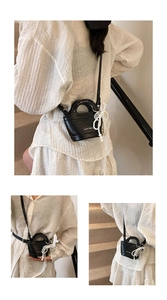 Detail of mini black bucket bag with lychee texture and pearl lace bow accessory