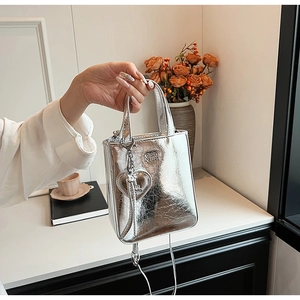 Détail d'un mini sac cabas argenté métallisé avec texture brillante et pendentif cœur