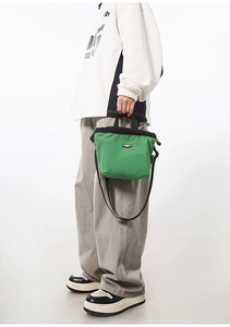 Green and black contrast nylon crossbody bag shown in a studio model photoshoot