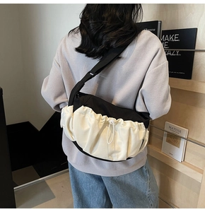 Detail view of a black and white drawstring dumpling crossbody bag with pleated texture