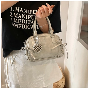 Detailansicht der perlbgrauen Boston-Tasche mit seitlichen Schleifen und Herzanhänger