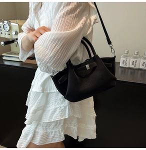 Gros plan du sac seau en cuir noir avec boucle en métal et bandoulière réglable