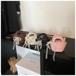 Detail of mini bucket bags in four colors with pearl lace bows and branding