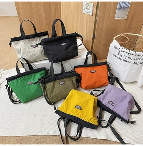 Detail of crinkled nylon tote bags in various colors with brand logo and detachable straps