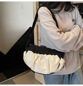 Detail of the black contrast drawstring crossbody bag worn over a gray sweatshirt