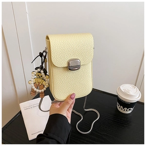 Detail of light yellow lychee grain leather phone bag with silver buckle and bear charm